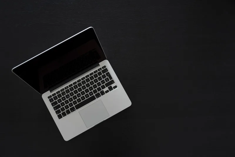 Overhead view of a laptop on a minimal dark desk workspace