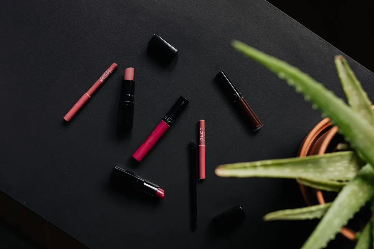 Overhead flatlay of lipsticks and makeup products arranged on a dark background