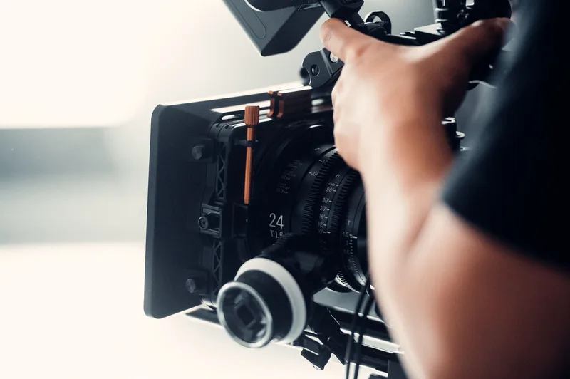 Close-up of a video camera lens being adjusted by hand during filming