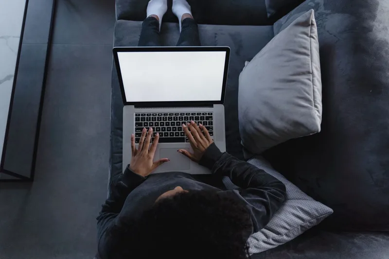 Laptop open on a couch viewed from above, showing a research workflow without revealing the creator’s identity