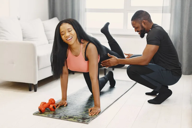 Man and woman exercising with weights in a bright home workout setting