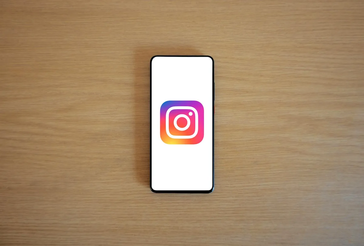 Dark phone screen showing a branded Instagram profile with a logo instead of a face, teal accent highlights