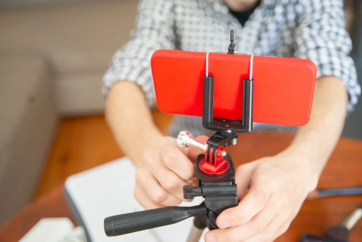 Close-up of hands setting up a smartphone on a tripod indoors, representing a faceless short-form filming setup