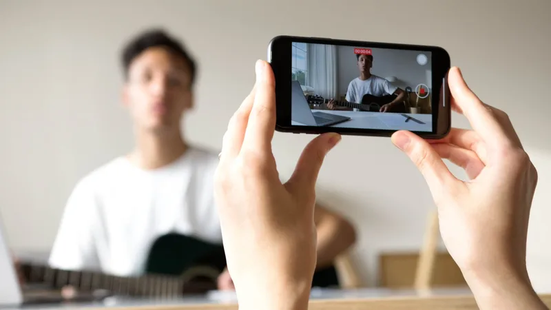 Person recording video content indoors using a smartphone, representing faceless content creation