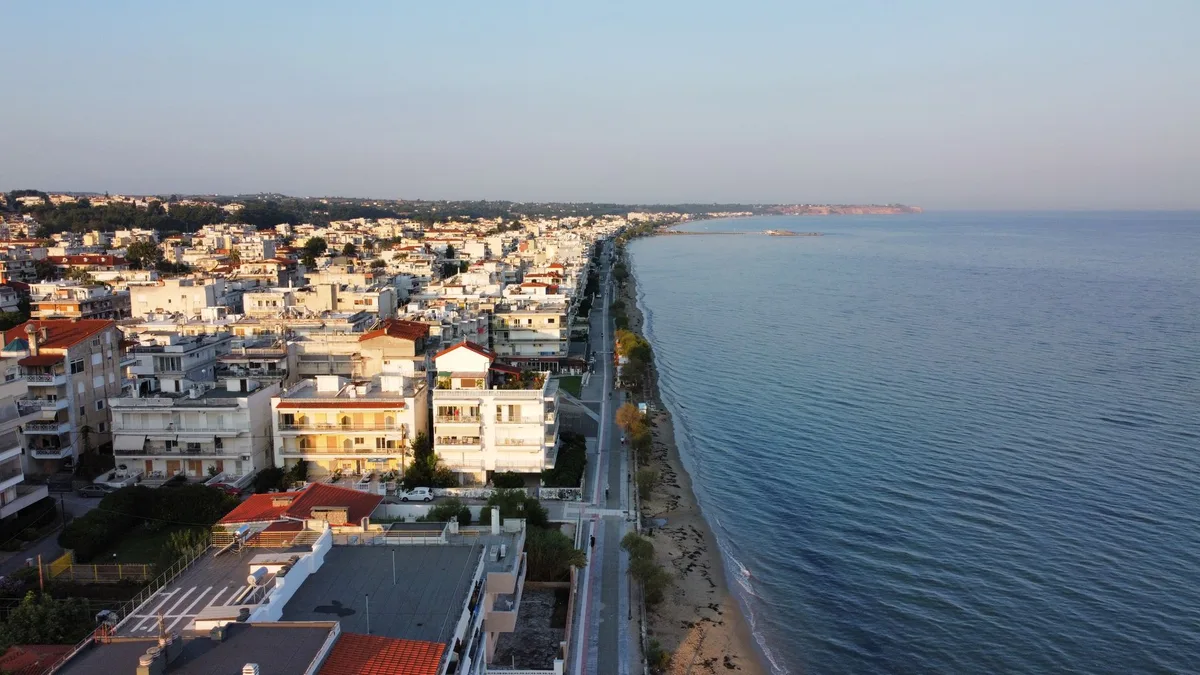 Aerial view of a coastal town with buildings and beach at sunset for a faceless travel YouTube channel