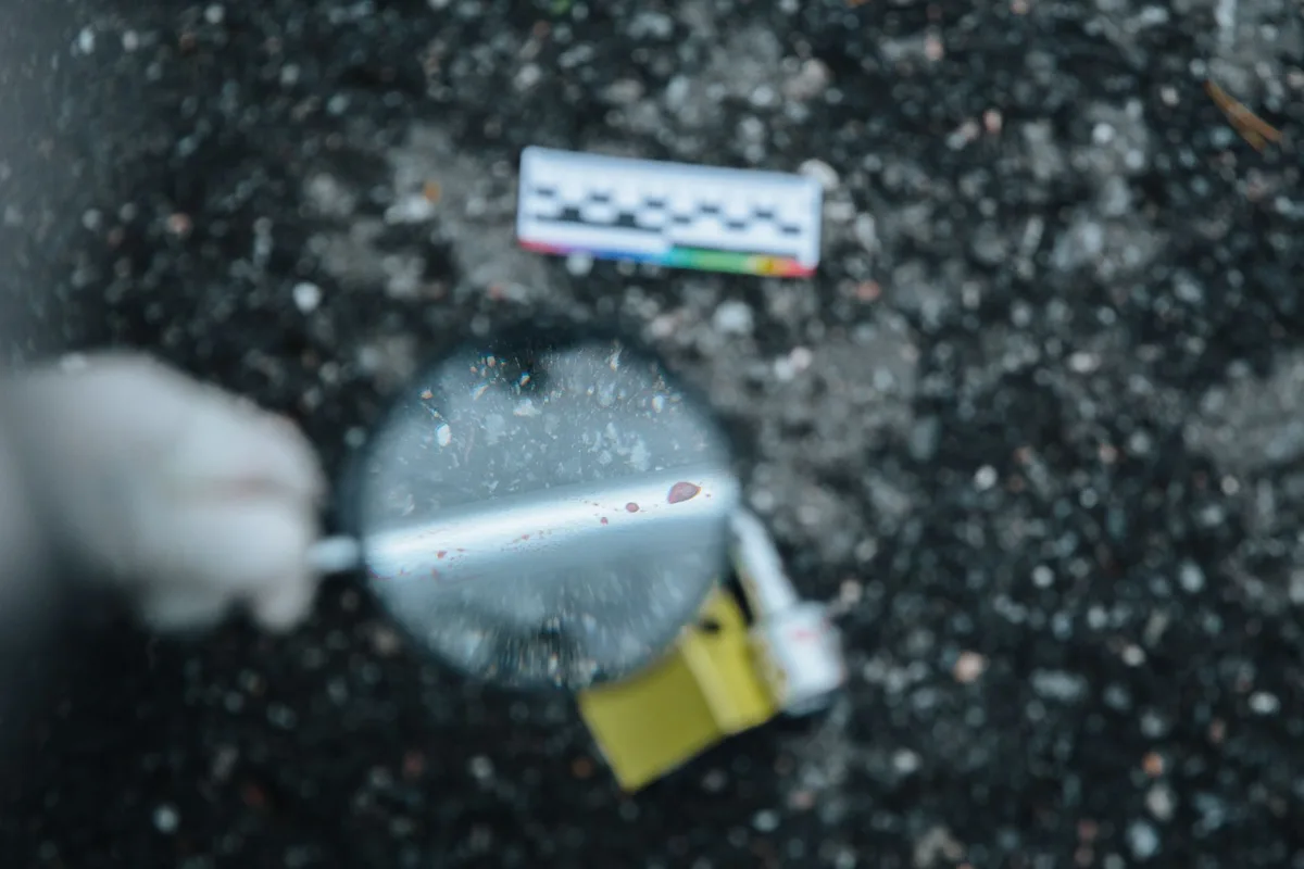 Dark atmospheric crime investigation scene with magnifying glass and documents on charcoal background