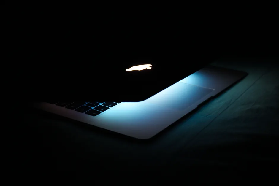 Laptop with a glowing keyboard in a dark room, screen only, no person visible